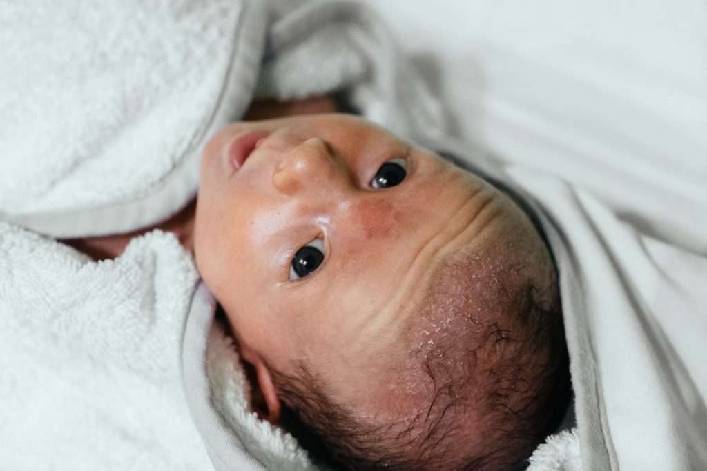 Freshly bathed newborn with delicate skin wrapped in a soft white bamboo towel
